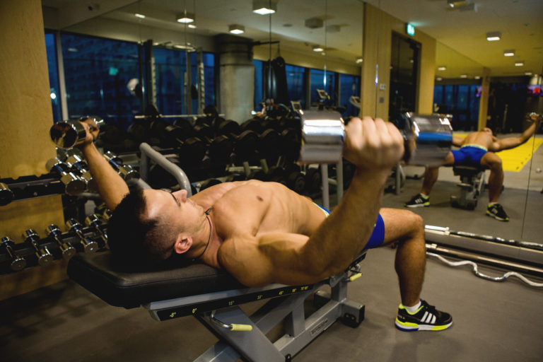 ćwiczący mężczyzna, ćwiczenia mięśni klatki piersiowej